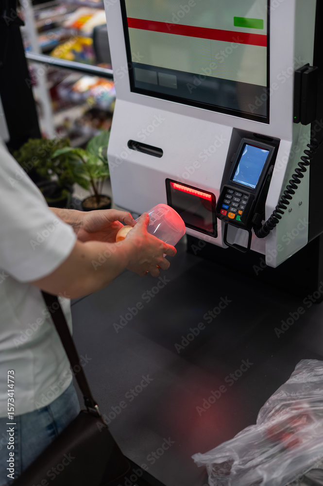 Naklejka premium A woman scans items at a self-checkout.