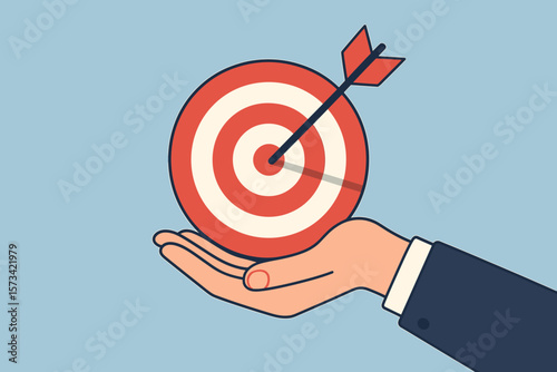 Businessman hand holding a target with arrow in the bullseye. Concept of goal, success, focus, objective, achievement, aspiration, strategy, accuracy and business mission.