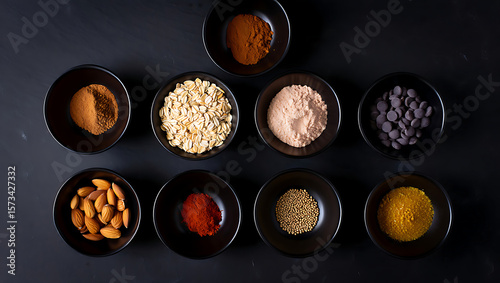 Dark Moody Flatlay:  Artisan Baking Ingredients in Black Bowls; Oats, Almonds, Spices, Chocolate Chips, and Sugar.
