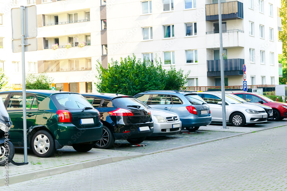 Naklejka premium Long row of cars parking tightly along city road street.Urban transportation infrastructure problems in residential district.vehicles parked by curb.