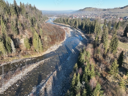 „Panorama Tatr z lotu ptaka” – Zdjęcie ukazuje majestatyczny krajobraz Tatr oświetlonych porannym słońcem. Widać wijącą się rzekę, doliny oraz gęsty las. To malownicza scena, oddająca spokój i piękno 