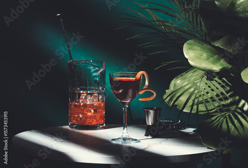Cocktail on a marble table with tropical plants in dimly lit bar setting at night