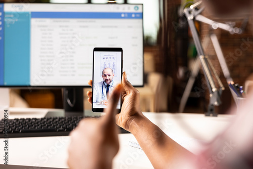 Selective focus on white male physician offering online consultation during video call with african american patient. Caucasian doctor on virtual meeting assisting black individual remotely.