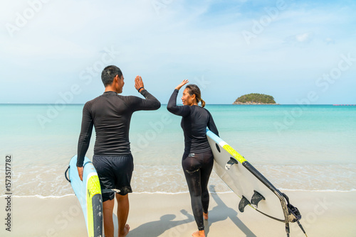 Canvas Print Happy Asian family man and woman couple enjoy water sports surfing at the sea on summer beach holiday vacation