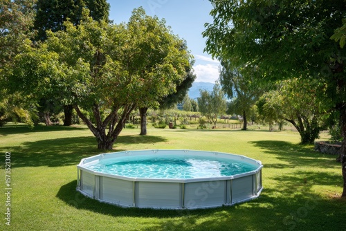 Above-ground swimming pool surrounded by lush greenery and trees in a sunny outdoor setting