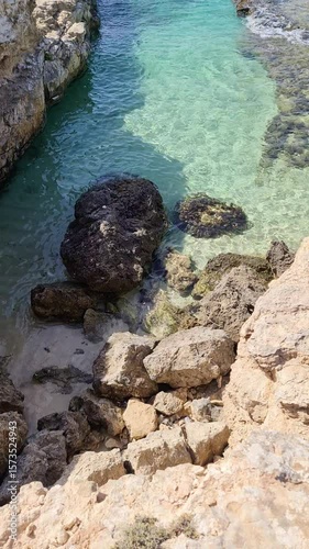Turquoise water flows between rocks on the coast of Puglia, Italy, creating a breathtaking natural spectacle.
