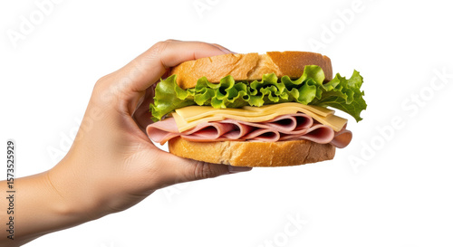 Hand holding a sandwich with ham cheese and lettuce against a black background close up view