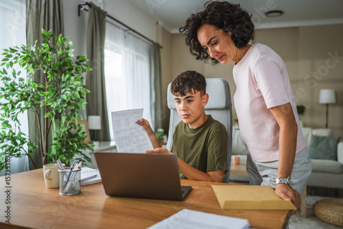 boy show document and talk on video call while his mom support him