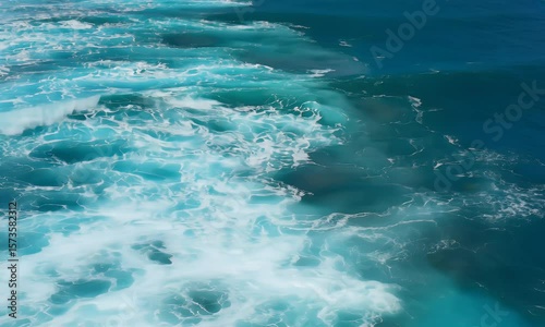 Scenic aerial view of turquoise ocean waves cascading and foaming on a bright sunny day