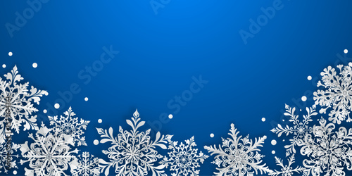 Christmas illustration featuring intricate paper snowflakes of varying sizes and designs located below, white on blue background.