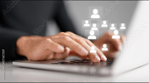 A person is typing on a laptop with a group of people on the screen