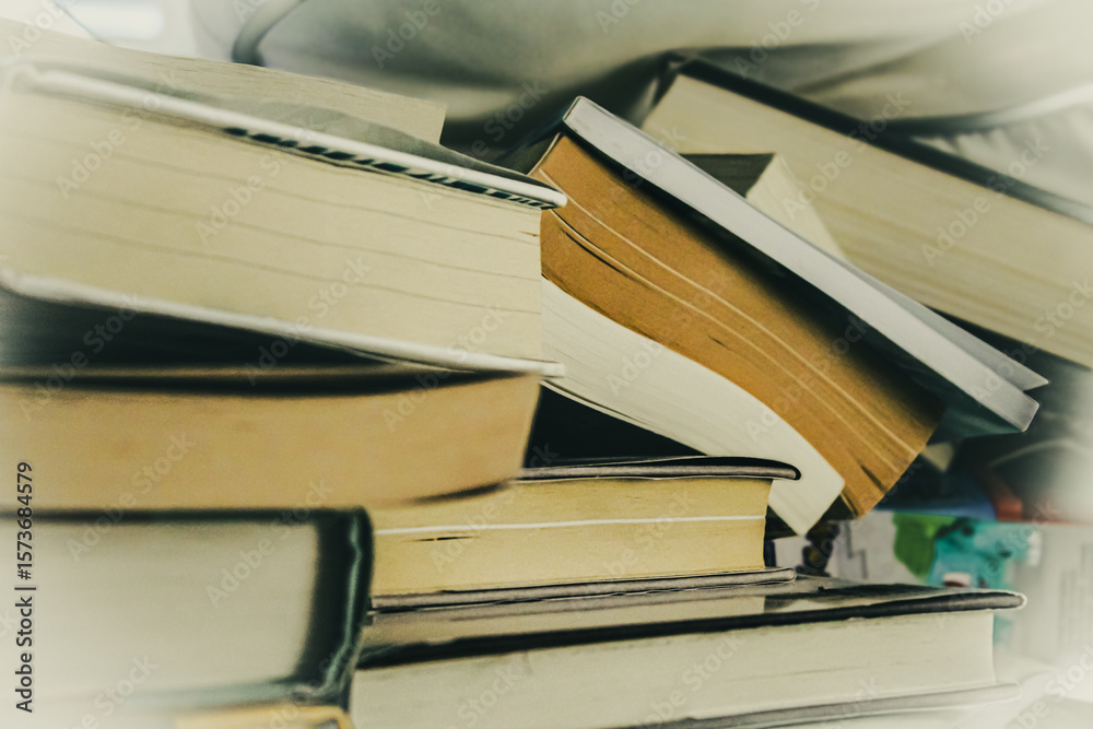 Fototapeta premium a stack of books randomly piled and tipping over. reading, learning, or knowledge abstract design element or background.