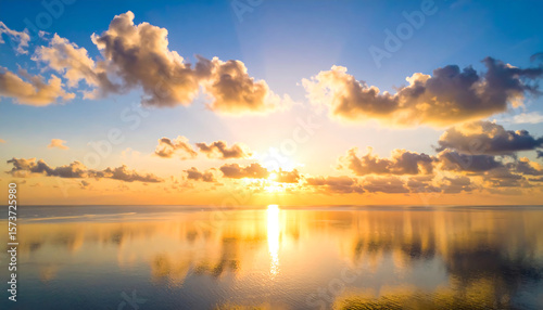 Golden sunset sky with clouds reflecting on calm ocean water creating peaceful and warm atmosphere