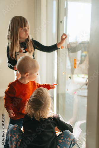 Siblings decorating window with halloween stickers