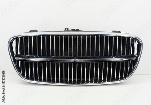 Close up of a shiny chrome car grill with vertical bars against a white studio background view
