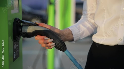Close-up of a beautiful female hand holding an electric car charger. 