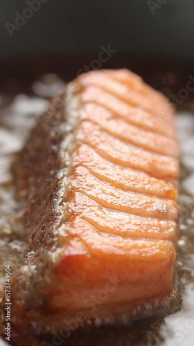 Pan-fried steelhead trout fish fillets in hot oil on non-stick frying pan. Close-up shot