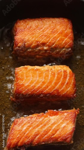 Pan-fried steelhead trout fish fillets in hot oil on non-stick frying pan. Top view shot