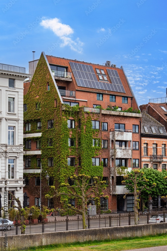 Fototapeta premium Explore sustainable architecture in Antwerp, Belgium. This eco-friendly building features a green facade and solar panels, merging modern design with nature in the heart of the city.