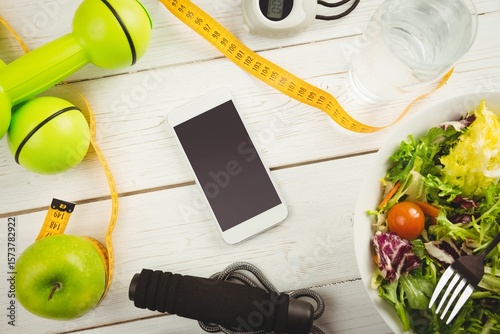 Overhead view of mobile phone and tape measure on wooden table