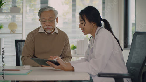 A compassionate doctor provides expert advice and care to a senior patient, utilizing modern technology for effective communication and medical consultation in a clinic setting.