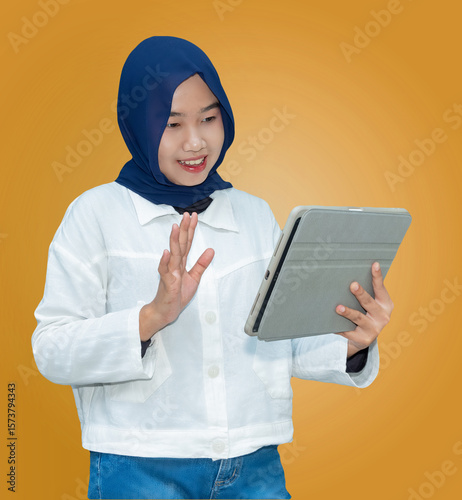 Cheerful Asian woman waving at tablet screen during video call. Suitable for concepts like online meeting, digital communication, or social connection.