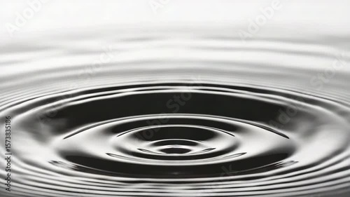 Drop of water creating ripple effect in calm pool surface with beautiful light reflection and texture