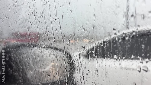 Traffic in rainy day with road view through car window with rain drops