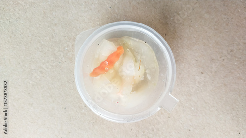 Fotografie Pickled vegetables in clear plastic container on textured background, showing ca