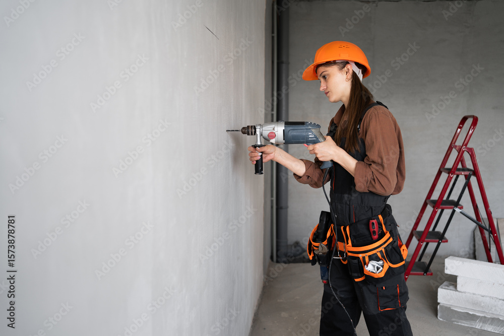 Fotografie Builder worker using drill perforator making hole in wall at construction site