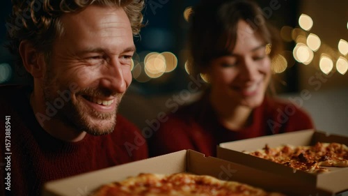 Happy young couple enjoying a cozy night with pizza and laughter in a warmly lit indoor setting