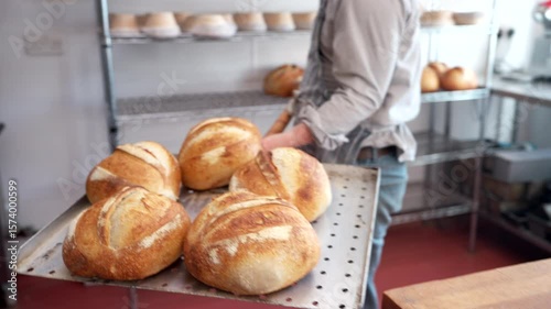Close Up Of Male Baker Taking Sourdough Loaves Out Of Oven With Paddle In Bakery
