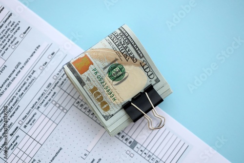 Big amount of United States USD dollar bills banknotes on table with 1040 tax return form photo