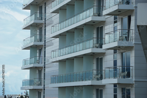Facade of white modern street building with many glass balconies. Urban architecture.