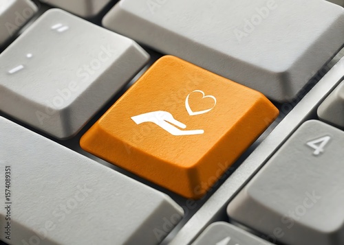 Hand holding heart icon on orange keyboard key high resolution photo