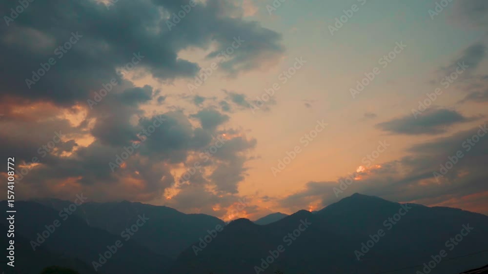 Landscape shot of sunset with clouds above the Himalayan mountains during the monsoon season as seen from Naggar near Manali in Himachal Pradesh, India. Clouds above the Himalayas in sunset. Landscape shot of sunset with clouds above the Himalayan mountains during the monsoon season as seen from Naggar near Manali in Himachal Pradesh, India. Clouds above the Himalayas in sunset.