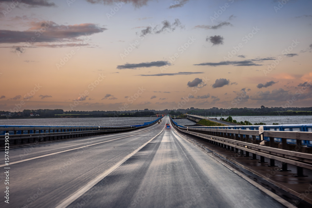 Long bridge over river. Sunset traffic. Cars on highway Long bridge over river. Sunset traffic. Cars on highway