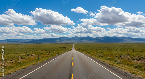Wide Open Rural Road with Blue Sky and Distant Mountains