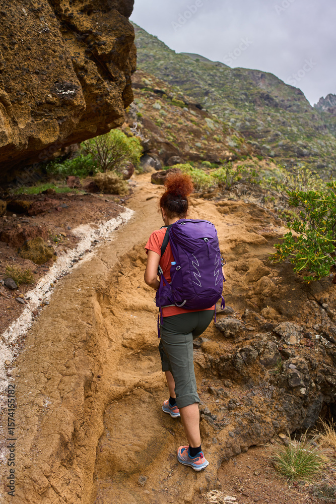 Naklejka premium Tourist hiking rugged volcanic trail