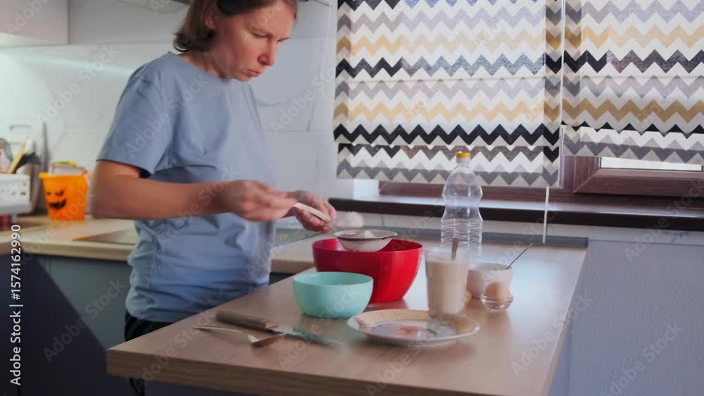 Woman combining flour, raw egg, and oil in a red bowl to prepare natural homemade dough. Cozy home kitchen atmosphere, fresh, simple ingredients and real cooking. Woman combining flour, raw egg, and oil in a red bowl to prepare natural homemade dough. Cozy home kitchen atmosphere, fresh, simple ingredients and real cooking.
