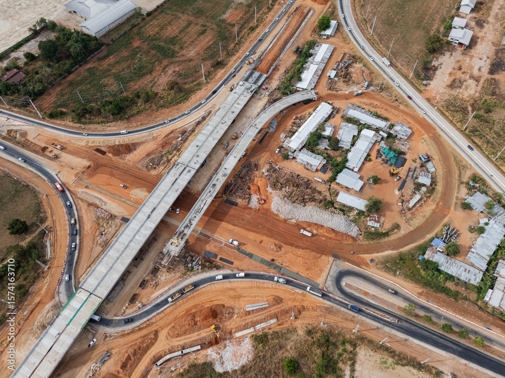 Obraz premium The construction site before the construction of the concrete bridge over the intersection by crane workers, tractors, and backhoes