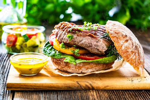 Tableau sur toile Takeaway sandwich with grilled beef steak and tomato served with fresh salad and