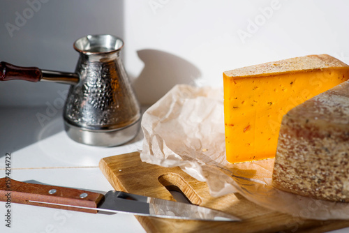 Pieces of fresh, aged, natural farm cheese on parchment paper on a wooden board. Unusual taste and quality of farm-fresh agricultural products.