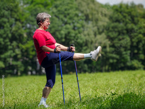Senior woman doing a series of warm-up exercises with walking poles