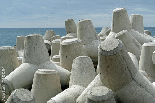 Coastal defences. Precast concrete blocks along a shore. This type of sea defence is known as rock armour. These  dissipate the energy of the waves, reducing coastal erosion. 