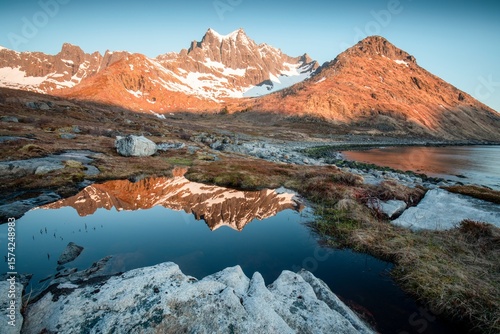Scenery of blue waters and green mountains with remnants of snow in spring under clear skies on the island of Senja, Senja municipality, Troms county, Mefjorden,  Norway, Europe. Tourist area