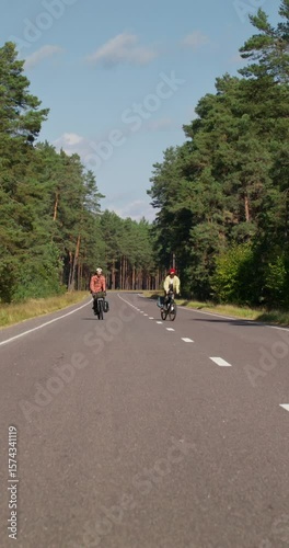Wallpaper Mural A young couple is riding a bike on a road in the middle of the forest. Active leisure on a sunny day Torontodigital.ca
