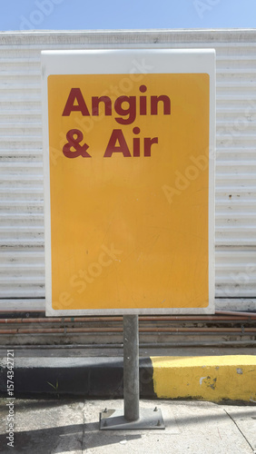 Signboard displaying Angin & Air in bright yellow on a sunny day