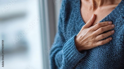 Chest pain or discomfort in a mature woman, with hand placed over heart area, symptom of potential cardiac issue, seeking medical advice, heart problem.