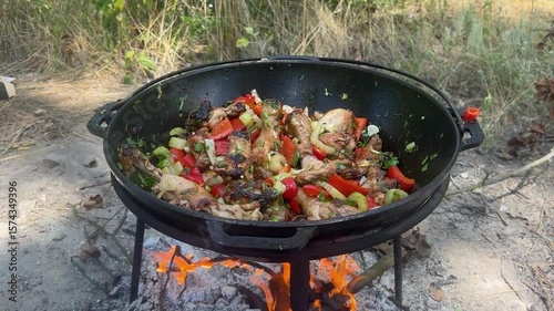 A dish on a fire in a cauldron. Stewing meat in a cauldron. The meat is stewed in a cauldron. Chicken meat is stewed in a cauldron.